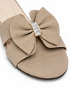 Close-up macro shot of gold baguette crystal brooch on beige textured bow slipper strap